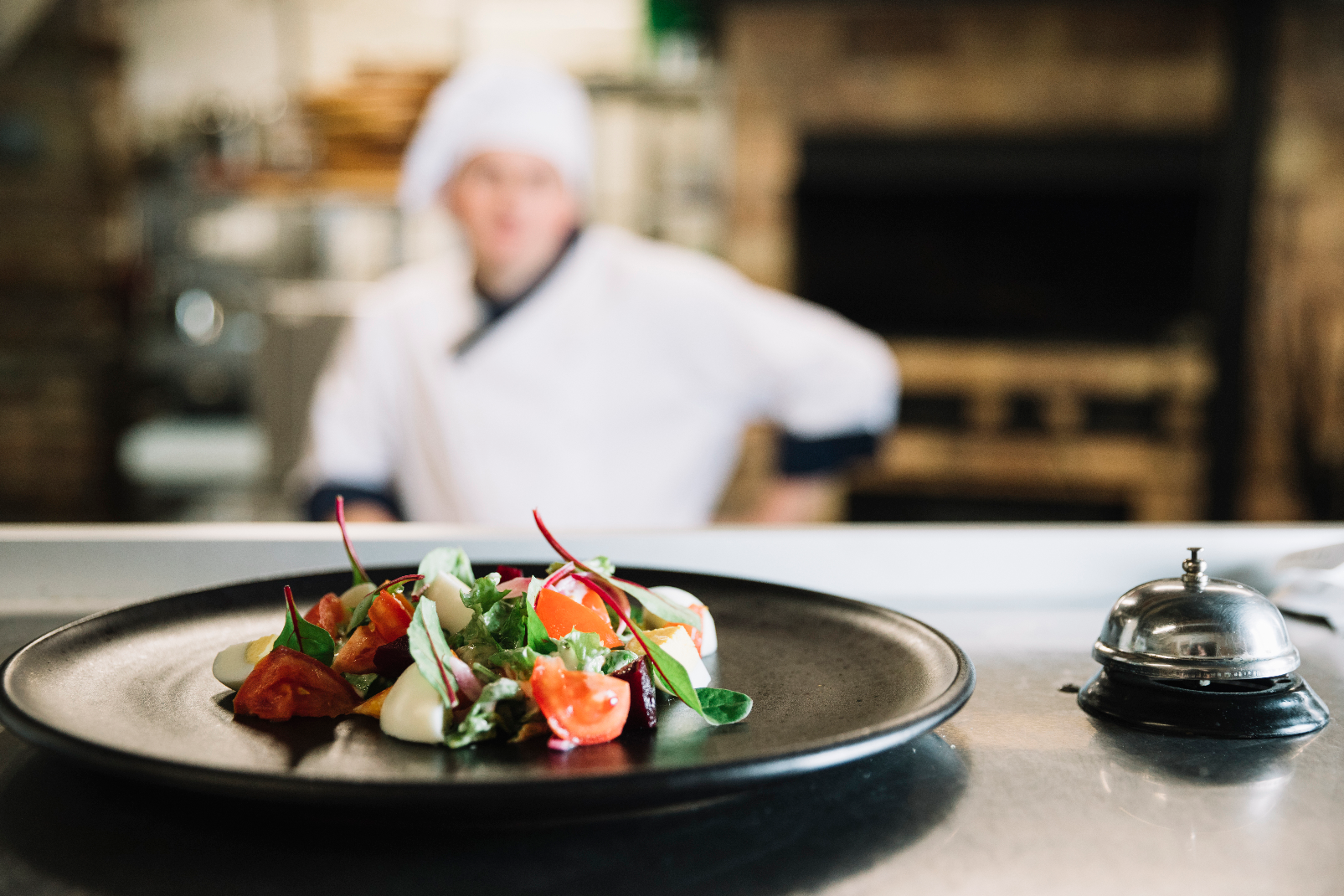 Fine dining salad plate with service bell and chef in white uniform 