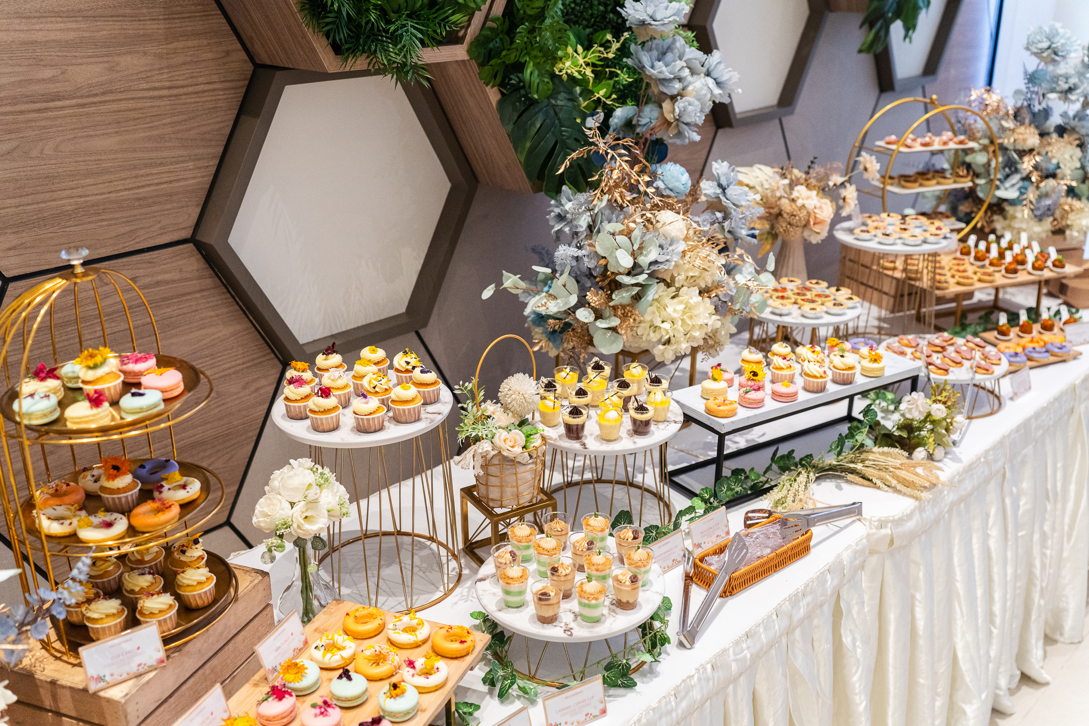 Wedding canape catering featuring an assortment of aesthetic dessert cup cakes and macaroons on elegant trays  