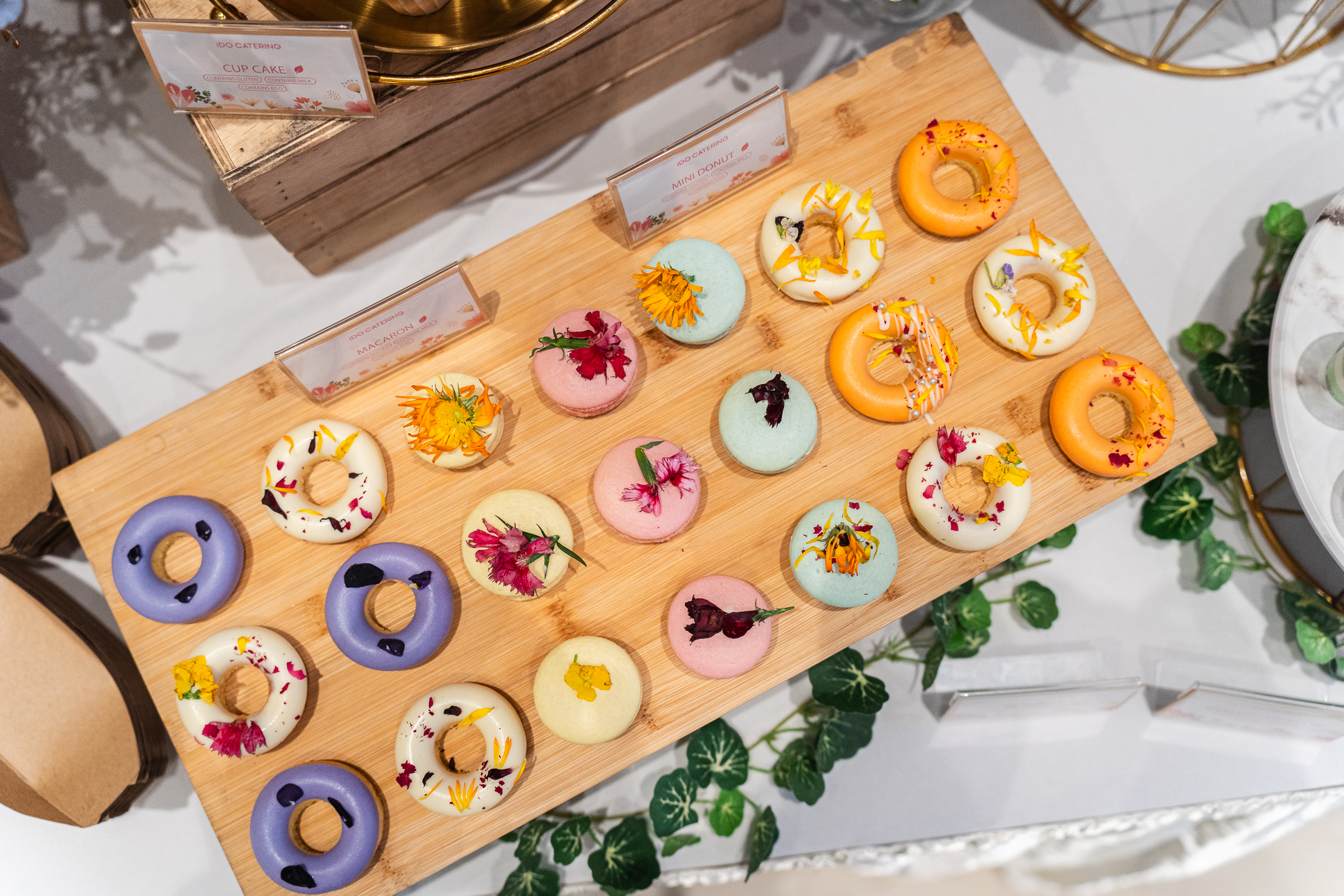 Colorful mini donuts and macaroons on wooden plate for wedding canape catering