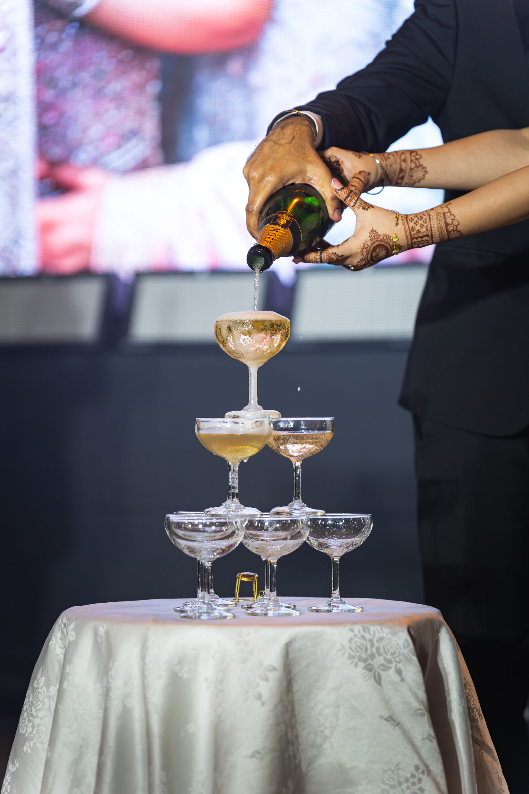 Couple pouring over champagne tower at emhub wedding catering event by idocatering